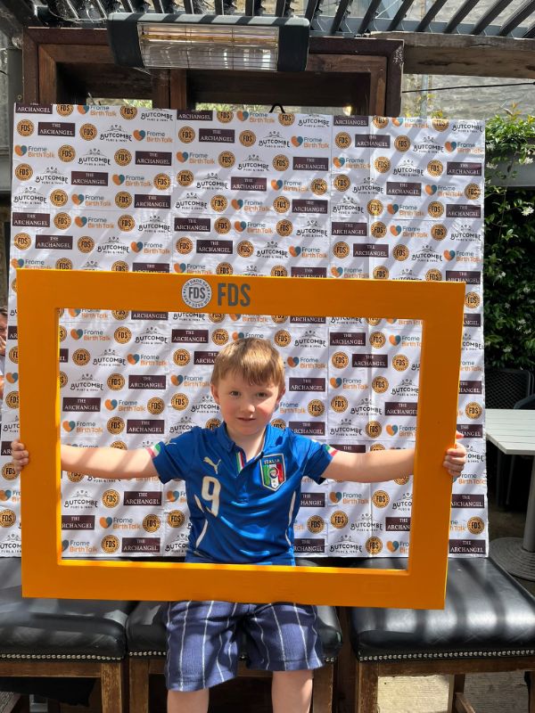 A boy in a football shirt holding up the orange FDS selfie frame