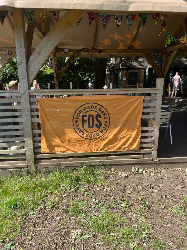 An orange For Dads Sake banner tied to a fence beneath bunting