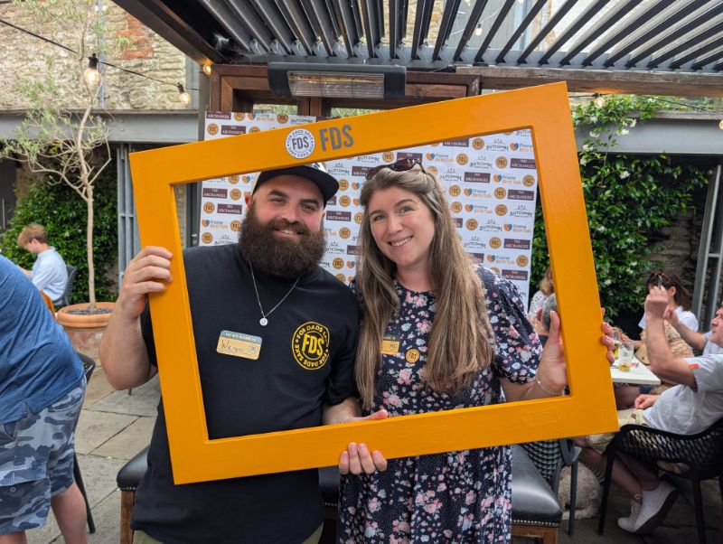 Two people smiling through the orange FDS selfie frame