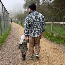 A dad walking hand in hand with his toddler